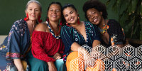 4 females in colourful clothing sitting together smiling for a photo