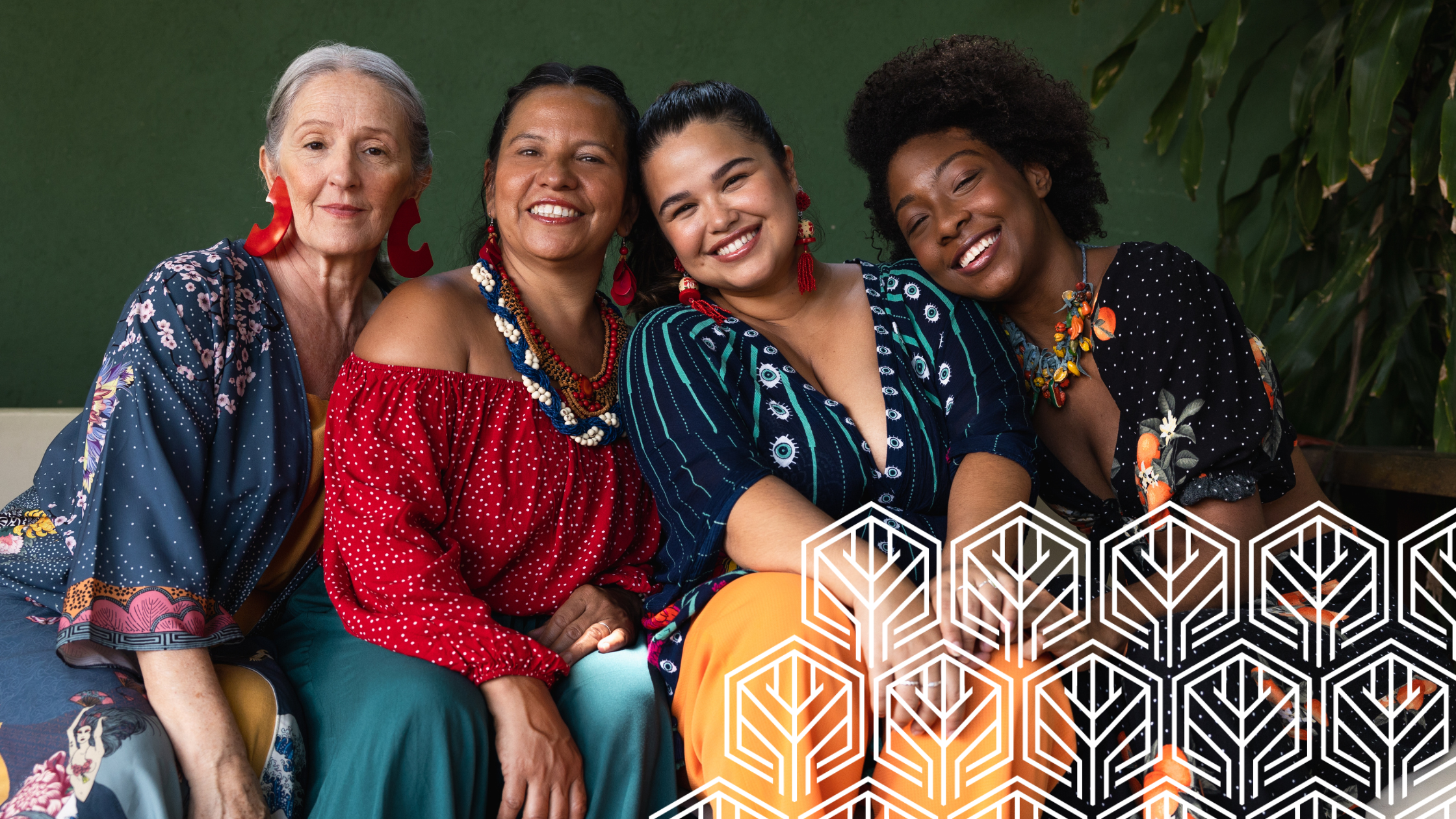 4 females in colourful clothing sitting together smiling for a photo