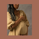 Black pregnant person with long braids and mustard coloured dress
